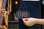 Close up of person turning closed sign on glass door to a bakery.