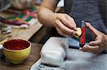 Close up of woman working in a Japanese porcelain workshop, holding red paint stick and sponge.