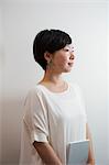 Profile view of woman with sort black hair wearing white shirt standing in art gallery.