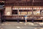 Young woman wearing blue dress and holding hat standing at Shinto Sakurai Shrine, Fukuoka, Japan.