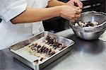 High angle close up of chef working in the kitchen of a Japanese sushi restaurant, placing Torigai, large cockles in a metal tray.