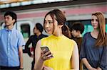 Small group of people standing on the platform of a subway station, Tokyo commuters.