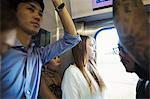 Small group of people standing on a subway train, Tokyo commuters.