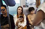 Three people sitting sidy by side on a subway train, Tokyo commuters.