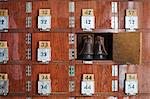 One pair of shoes in a shoe locker with an open door. Lockers in a row, with numbers.