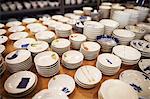 High angle close up of large selection of small white bowls in a Japanese porcelain workshop.