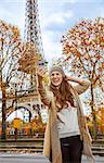 Autumn getaways in Paris. smiling young elegant woman in Paris, France taking selfie with phone