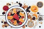 Healthy food for breakfast with granola, fresh fruit, nuts, pollen grain, yoghurt, acai berry powder and chia seed with foods high in omega 3, protein, antioxidants, anthocyanins, minerals and vitamins on  rustic white wood table background, top view.