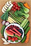 Health food for healthy eating concept with fresh vegetables and fruit on cork background, high in antioxidants, anthocyanins, minerals, vitamins and dietary fiber. Top view.