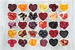 Food for healthy living with fruit, grains, vegetables and pulses in heart shped dishes on rustic wood background. Health foods high in antioxidants, anthocyanins, vitamins and minerals.