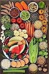 Healthy diet food concept with a selection of fruit, vegetables, seeds, grains, cereals, herbs and spices with foods high in vitamins, minerals, anthocyanins, antioxidants and fiber on oak background top view.