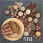 High fiber health food concept with fresh whole grain bread, nuts, seeds, grains and cereals. Foods high in antioxidants, omega 3 fatty acids and vitamins. Rustic background, top view.