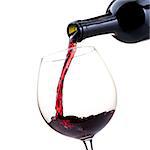 Pouring red wine from a bottle into a wineglass: wine tasting and celebration