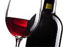 Excellent red wine tasting: wine bottle and wineglass on white background, close up