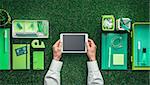 Businessman using a digital tablet on a grass desktop; green business, technology and communication concept