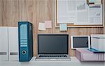 Laptop and folders on a shelf in the office, pinboard on the background, business workspace and technology