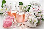 Aroma oil, sea salt, and apple blossom flower on wooden background