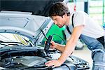 Mechanic man with diagnostic tool in car workshop