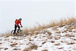 Cyclist in Red Riding the Mountain Bike on the Snowy Trail. Extreme Winter Sport and Enduro Biking Concept.