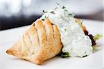 Traditional russian pie - coulibiac. Baked puff pastry filled with smoked salmon, served with sour cream sauce