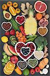 Health food for healthy eating concept with fruit, vegetables, seeds, nuts, tea, pollen grain, herbs and spices, super foods high in omega 3 fatty acids, antioxidants, anthocyanins, fiber, minerals and vitamins. Top view on slate.