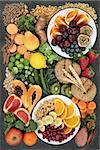Healthy high fiber dietary food concept with fruit, vegetables, legumes, nuts, spice, cereals, whole wheat pasta and whole grain bread rolls on marble, top view. Foods high in antioxidants, anthocyanins, omega 3 fatty acids and vitamins.