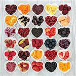 Healthy eating super food to promote good health with fruit, vegetables, grains and pulses in heart shaped bowls on rustic wood background. High in anthocyanins, antioxidants, minerals and vitamins.