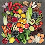 Healthy diet food concept with fresh fruit, vegetables, pulses, nuts, herbs, coffee and dark chocolate. Super foods high in antioxidants, anthocyanins, fiber and vitamins. Top view rustic background.