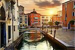 Venetian cityscape with water canal and small bridge at sunrise, Italy