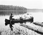 1920s MAN HUNTING GUIDE PADDLING CANOE IN LAKE CARRYING MOOSE AND DEER CARCASSES