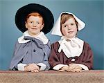 1950s 1960s BOY GIRL IN PILGRIM COSTUMES FOR ELEMENTARY SCHOOL THANKSGIVING PLAY LOOKING AT CAMERA