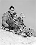 1930s 1940s FATHER TWO CHILDREN ON SLED IN SNOW GOING DOWN HILL