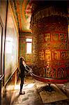 Woman praying at a Buddhist prayer wheel in Bouddha (Boudhanath) temple, UNESCO World Heritage Site, Kathmandu, Nepal, Asia