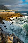 Seascape across stormy sea and rocks in setting sun at Sievers Point, Hermanus, South Africa, Africa