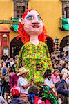 Mojiganga, giant puppet with crowd of people in the street at the St Michael Archangel Festival procession in San Miguel de Allende, Mexico