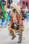 Close-up of an indigenous tribal dancer wearing costume with a skull mask and blond wig in the St Michael Archangel Festival parade in San Miguel de Allende, Mexico