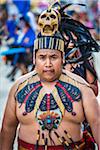 Portrait of male, indigenous tribal dancer looking at the camera wearing beaded collar and skull headdress in the St Michael Archangel Festival parade in San Miguel de Allende, Mexico