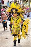 Close-up of a male, indigenous tribal dancer wearing yellow feathered costume and headdress in the St Michael Archangel Festival parade in San Miguel de Allende, Mexico