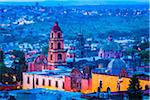 The pink stone bell tower of the Oratorio de San Felipe Neri and overview of the city at dusk in San Miguel de Allende, Mexico