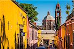 Traditional buildings with lanterns on street showing the bell tower and domed tower of the Church of San Francisco in San Miguel de Allende, Mexico