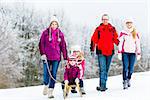 Family with kids having winter walk in snow with fun