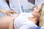 Pregnant woman doing ultrasound scan in the prenatal clinic, mother worried about health of her future baby, happy pregnancy time