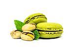 Sweet green pistachio flavor macaroons with nuts and leaves isolated on white background. Two french macarons