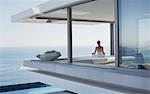 Serene woman meditating on modern, luxury home showcase exterior patio with ocean view