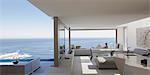 Woman relaxing on modern, luxury home showcase patio with sunny ocean view