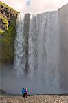 A couple staring at Skogafoss waterfall, Skogar, Sudurland, Iceland