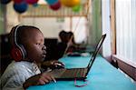 School boy child sitting and concentrating at a laptop