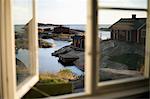 Wooden houses on rocky seashore seen through window