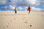 Two children running along the beach