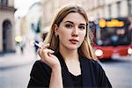 Portrait of young woman smoking in street